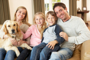Happy Family Sitting On Couch With Dog