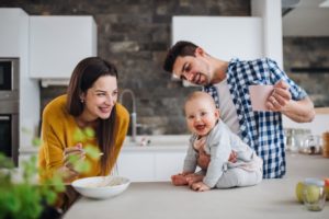 Happy Couple Feeding Baby On Kitchen Counter