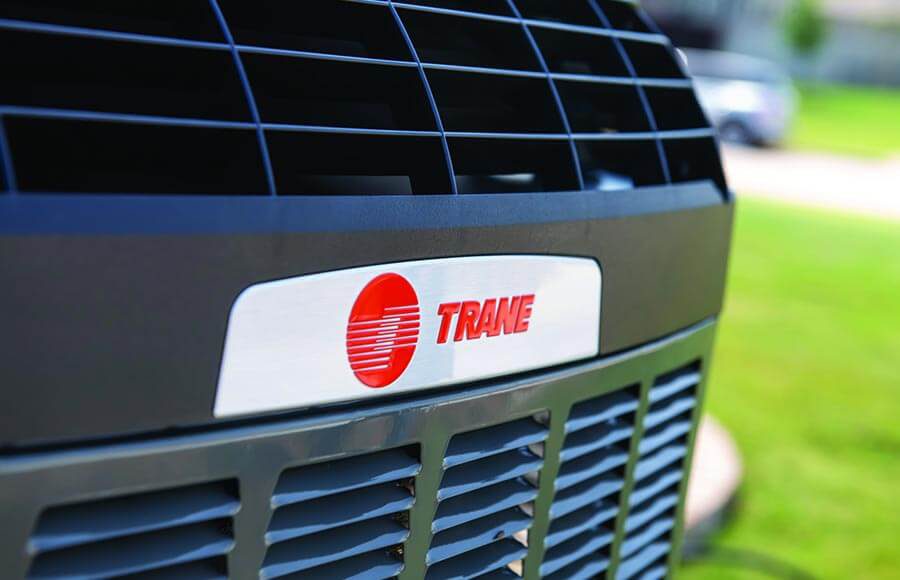 Close-up of a Trane outdoor HVAC unit showing the brand logo on the protective grille
